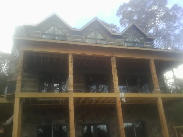 Dormers and porch framing on a large log home under construction — Roof Coating work by our crew in Haverhill