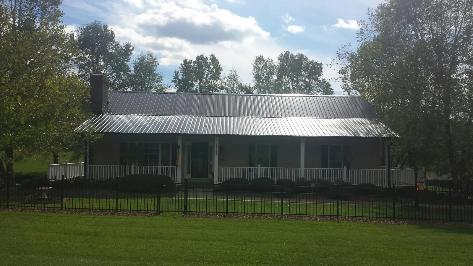 Gray metal roof on a brick ranch with a full width front porch — Gutter Guard Installation work by our crew in Haverhill